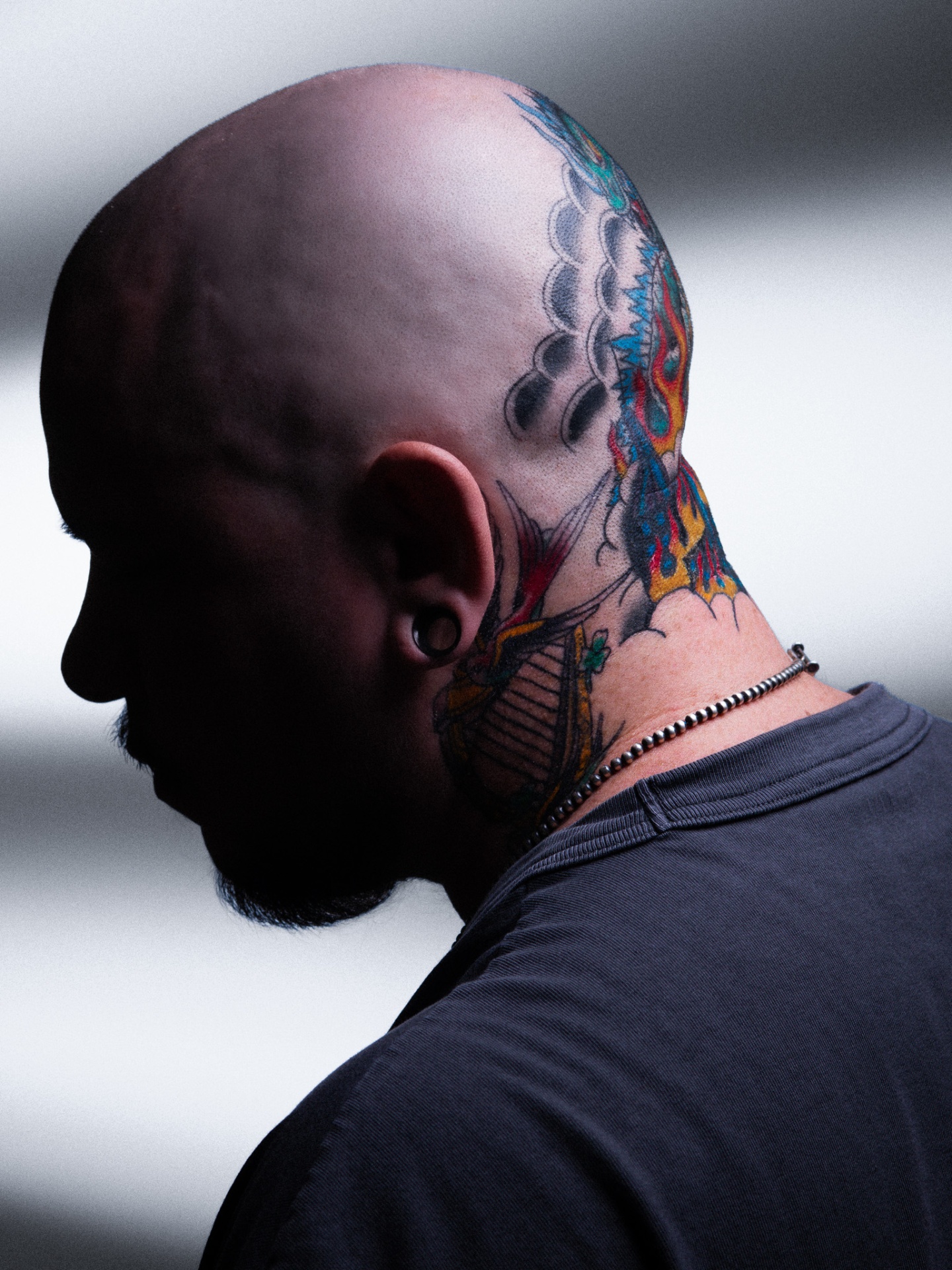 Back of a bald head and neck covered in colorful traditional tattoos